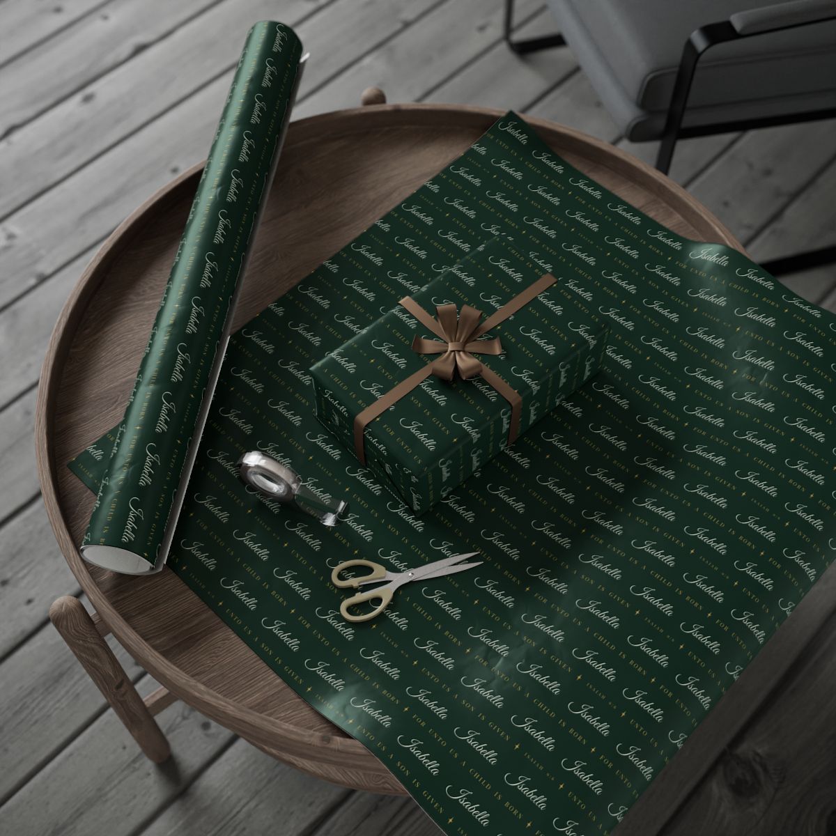 Personalized Isaiah 9:6 scripture Christmas paper in evergreen and gold: the roll and a wrapped gift on a wooden table