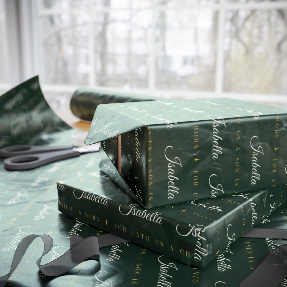 Two gifts wrapped in personalized Isaiah 9:6 scripture Christmas paper in evergreen and gold with the name Isabella, on a table by the window