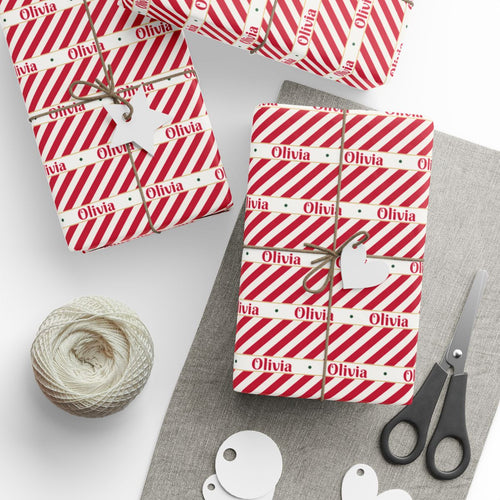 Gifts wrapped in personalized candy cane stripe Christmas paper with the name Olivia, tied with twine
