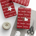Gifts wrapped in personalized classic red Christmas paper with the name Charlotte, tied with twine