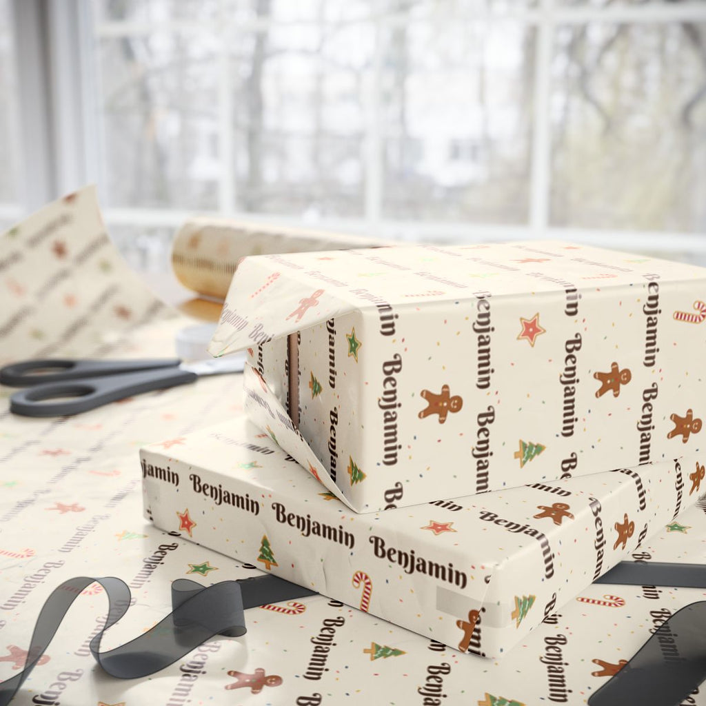 Two gifts wrapped in personalized Christmas cookies paper in cream with the name Benjamin, on a table by the window