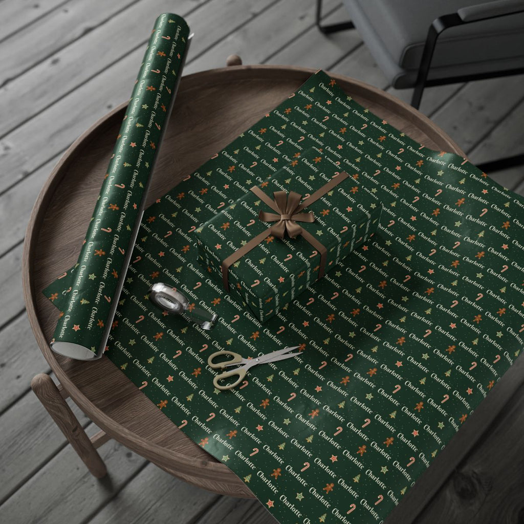 Personalized Christmas cookies paper in forest green: the roll and a wrapped gift on a wooden table