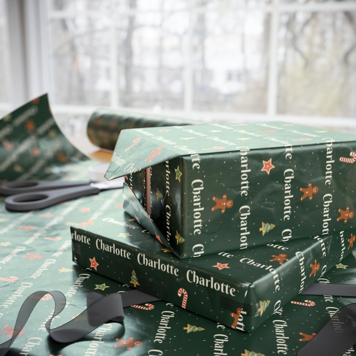 Two gifts wrapped in personalized Christmas cookies paper in forest green with the name Charlotte, on a table by the window