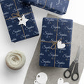 Gifts wrapped in personalized navy snowflake Christmas paper with the name Sophia in white script, tied with twine
