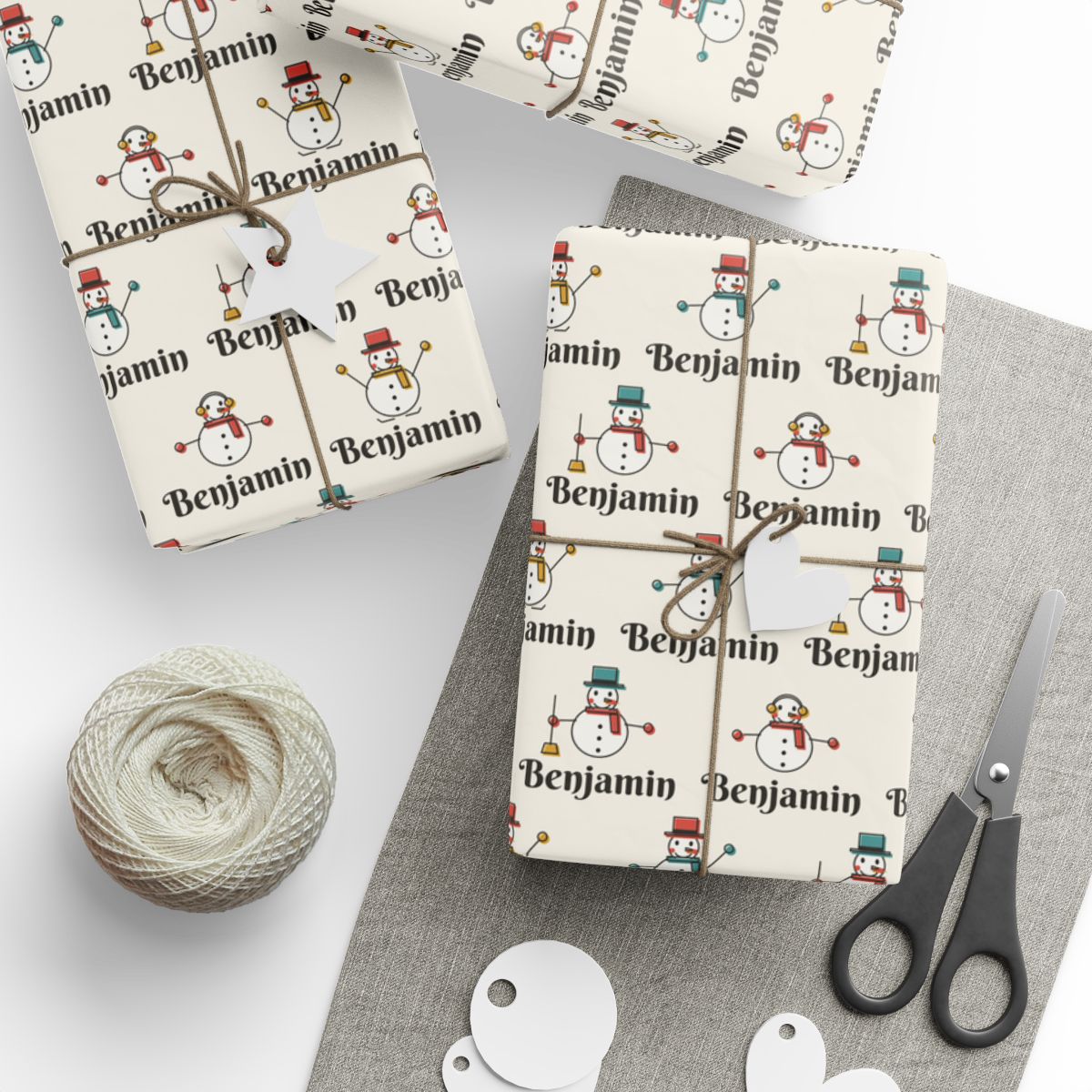 Gifts wrapped in personalized snowman parade Christmas paper with the name Benjamin, tied with twine
