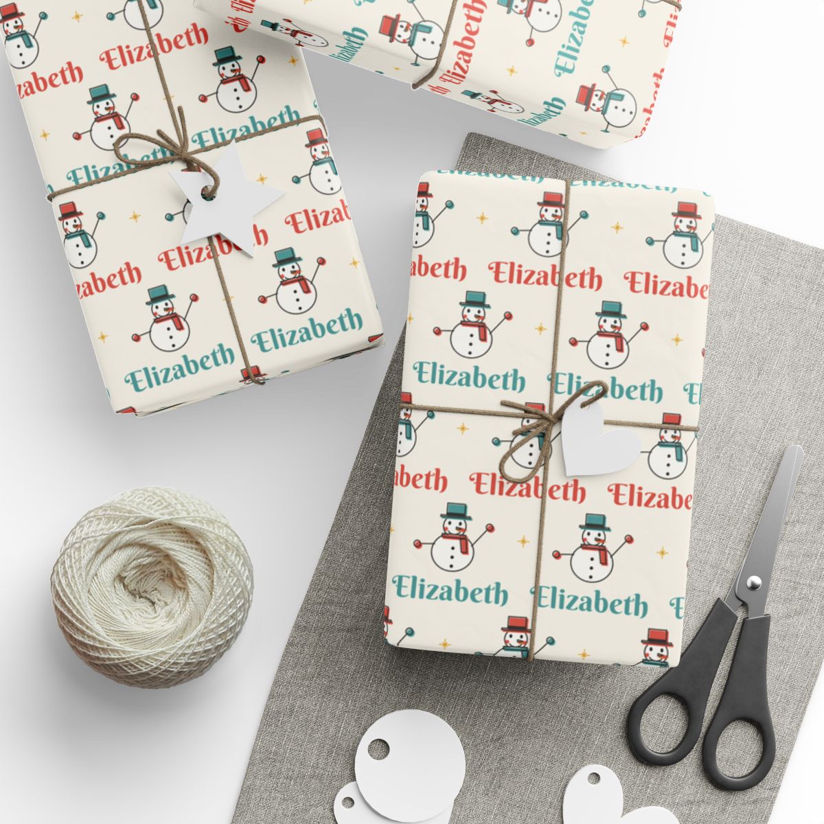 Gifts wrapped in personalized retro snowman Christmas paper with the name Elizabeth, tied with twine